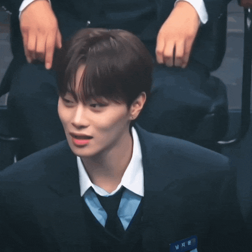 a young man wearing a suit and tie is looking at the camera