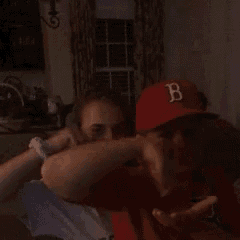 a man wearing a red hat with the letter b on it is hugging a woman
