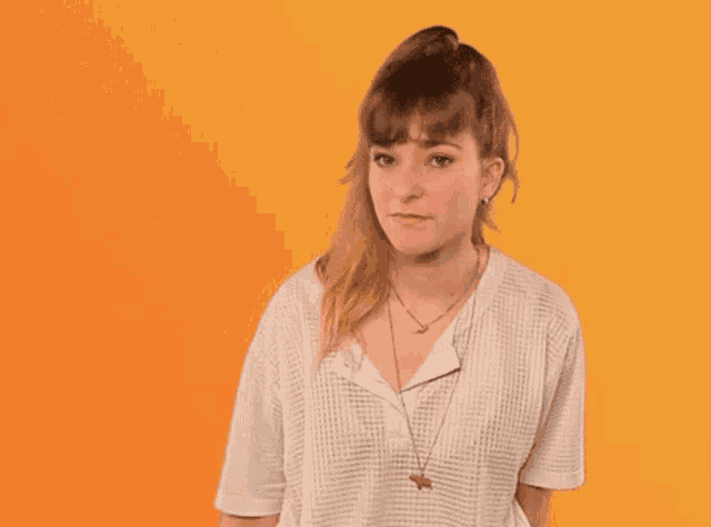 a woman wearing a white shirt and a necklace is giving the middle finger