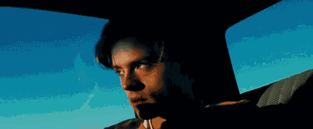 a man is looking out the window of a car with a blue sky in the background