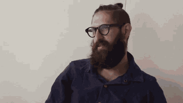 a man with a beard wearing glasses and a bun