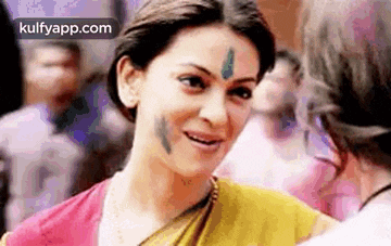 a woman with a bindi on her forehead is smiling while talking to another woman .