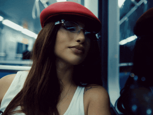 a woman wearing a red hat and glasses looks to the side