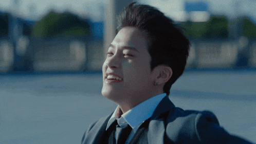 a young man in a suit and tie is smiling with his eyes closed