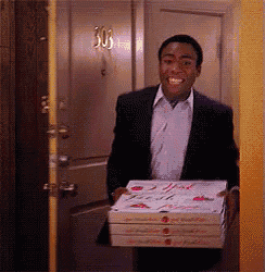 a man in a suit is holding three boxes of pizza