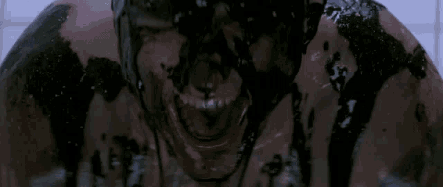 a man with his face covered in black liquid is smiling