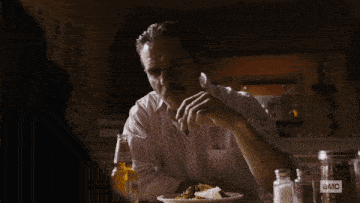 a man sits at a table with a bottle of corona beer