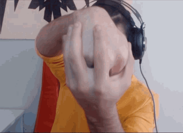 a man wearing headphones covering his face with his hand