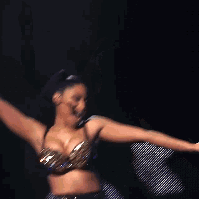 a woman in a black bra and gold skirt is dancing on a stage