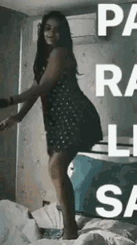 a woman in a polka dot dress is standing on a bed .