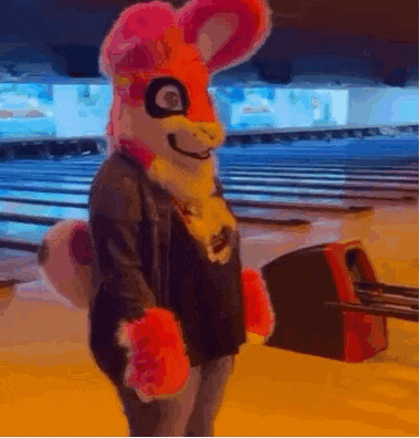 a person in a bunny costume is standing in front of a bowling alley holding a bowling ball .