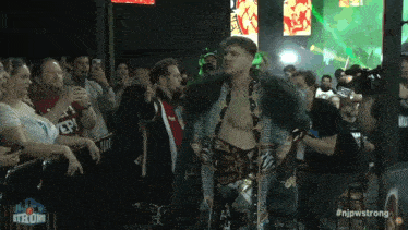 a man in a greek key coat walks through a crowd