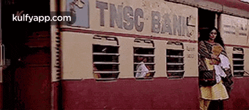 a woman is standing in front of a train that says tnsc bank