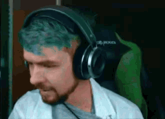 a man with green hair is wearing headphones while sitting in a green chair .
