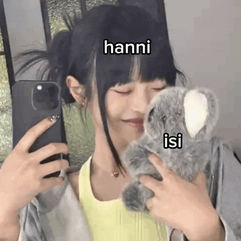 a girl is taking a selfie with her phone while holding a stuffed koala bear .