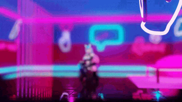 a blurred image of a person standing in front of a neon sign in a room .