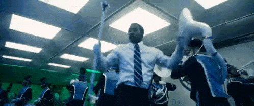 a man in a suit and tie is dancing with a group of people .