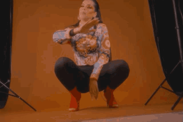 a woman squatting in front of a yellow background