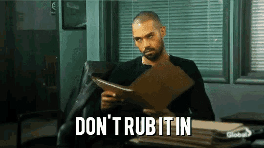 a man sitting at a desk with a clipboard and the words " don 't rub it in " on the bottom