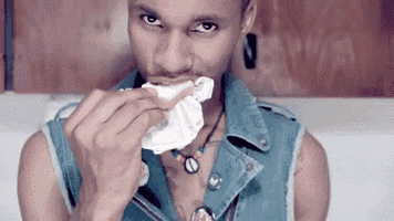 a man wearing a denim vest is eating something