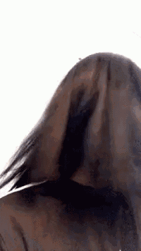 a close up of a person 's back with their hair blowing in the wind against a white background .