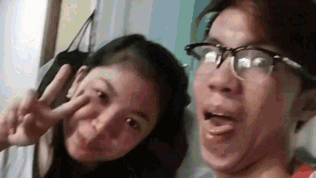 a boy and a girl are posing for a picture and the boy is wearing glasses .