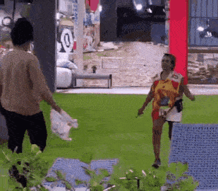 a man and a woman are standing in a grassy area .