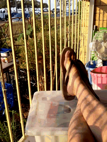 a person wearing flip flops is sitting on a container
