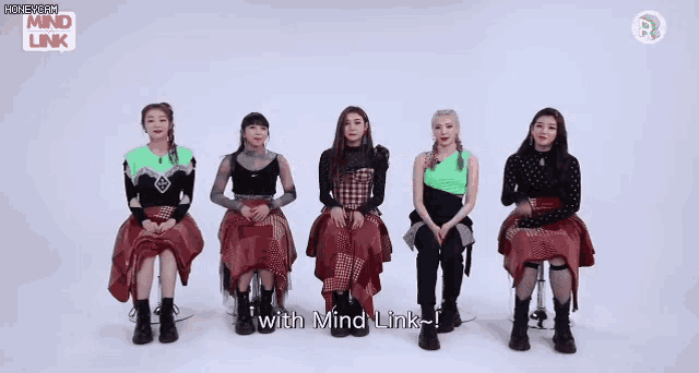 a group of girls are sitting in a row and pointing at each other with the words " with mind link " on the bottom