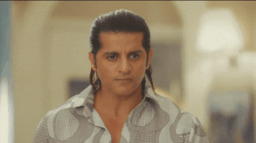 a man with a ponytail is wearing a shirt that has a pattern on it