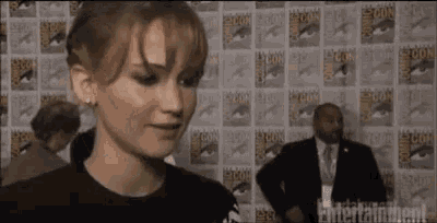 a woman is standing in front of a wall with comic con on it