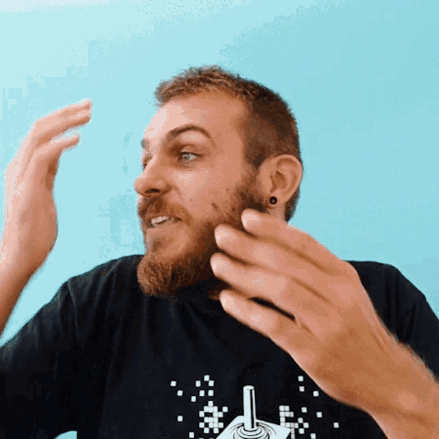 a man with a beard is wearing a black t-shirt with a joystick on it