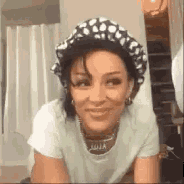 a woman wearing a hat and a t-shirt is smiling in a room .