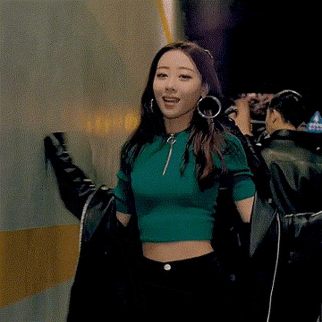 a woman wearing a green crop top and black earrings