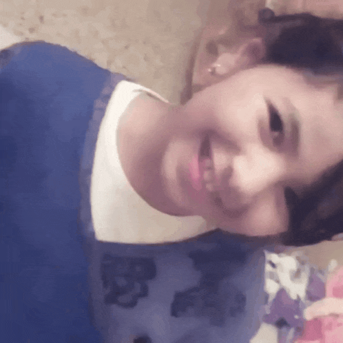 a young girl wearing a blue sweater and a white shirt is smiling