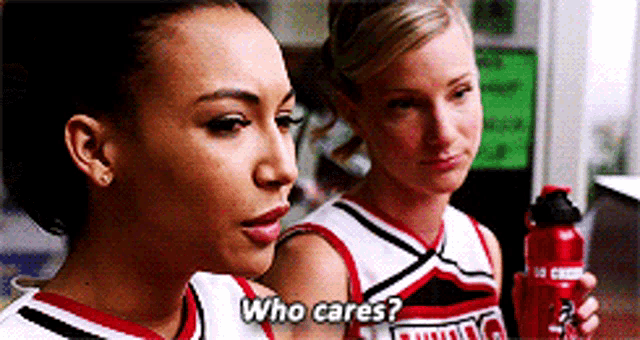 two cheerleaders are standing next to each other and one of them is holding a red water bottle and says who cares
