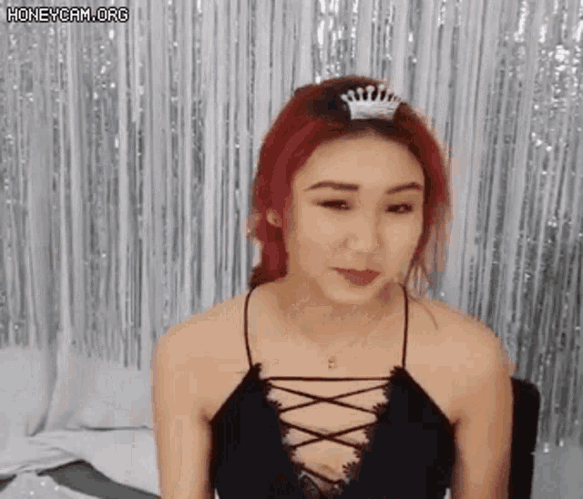 a woman with red hair is wearing a crown and a black top .