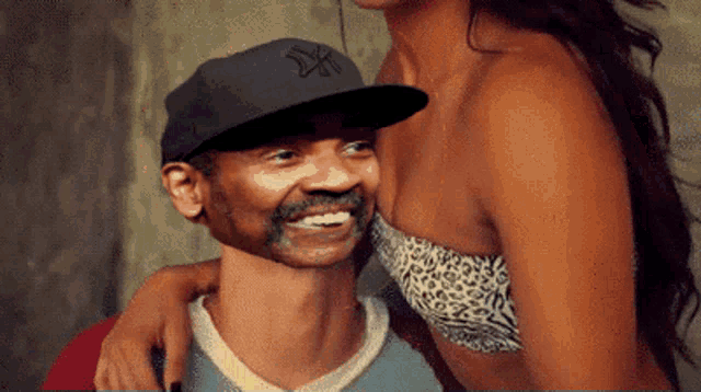 a man wearing a ny hat smiles next to a woman