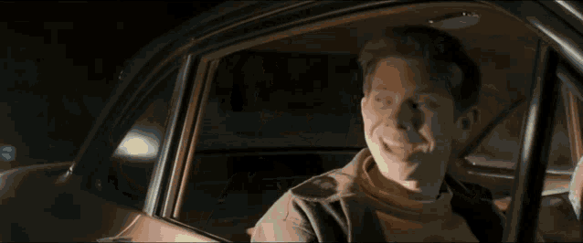 a man is smiling while sitting in the back of a car