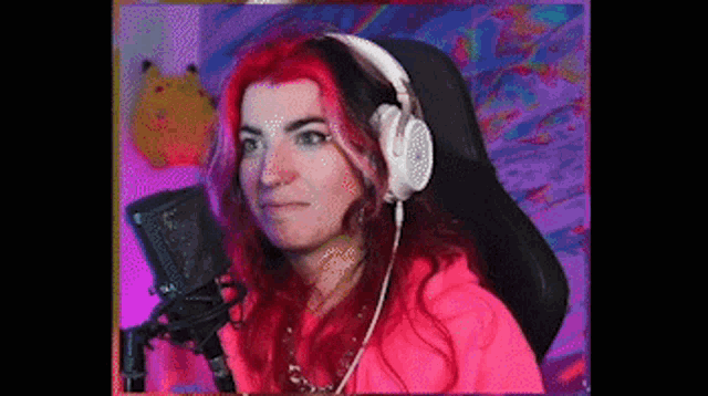 a woman with red hair is wearing headphones while sitting in front of a microphone .