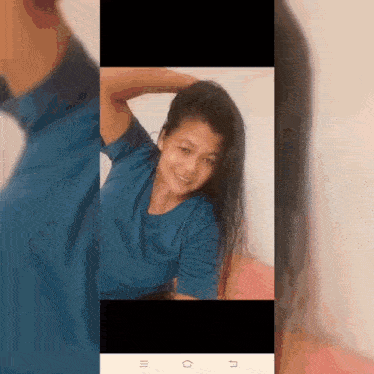 a woman in a blue shirt is smiling while holding her hair