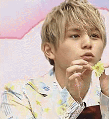 a young man is holding a flower in his hand and eating it .