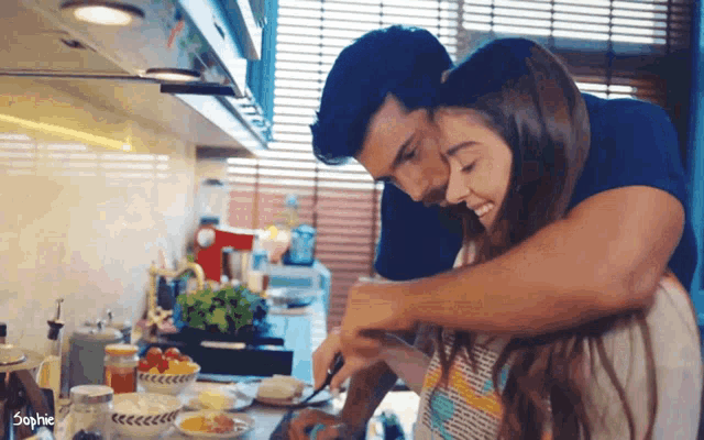a man is hugging a woman in a kitchen with the word sophie on the bottom right