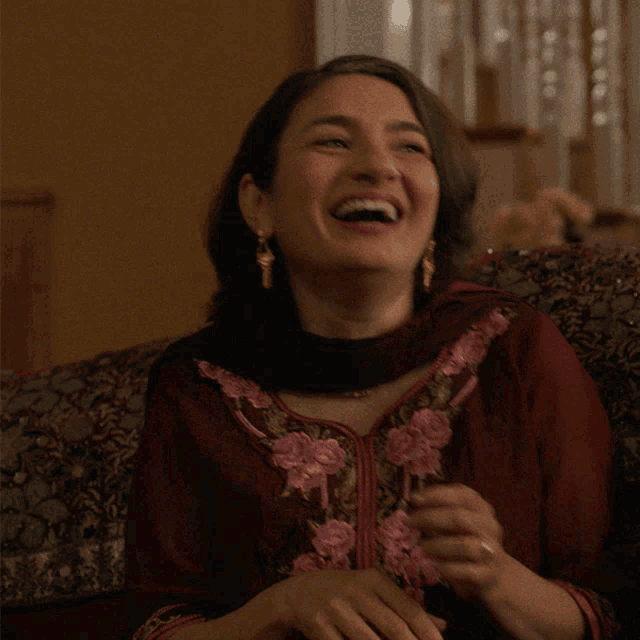 a woman sitting on a couch laughing with her mouth open