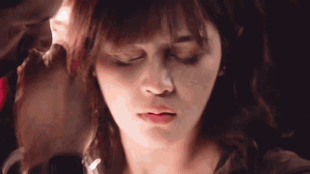 a close up of a woman 's face with her eyes closed and a man 's hand on her head .