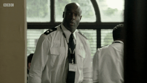 a man in a white shirt and tie is standing in front of a window with bbc written on the bottom