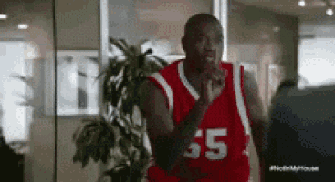 a man wearing a red basketball jersey with the number 55 on it is standing in front of a plant .