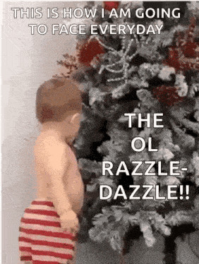 a baby is standing in front of a christmas tree with a funny caption .