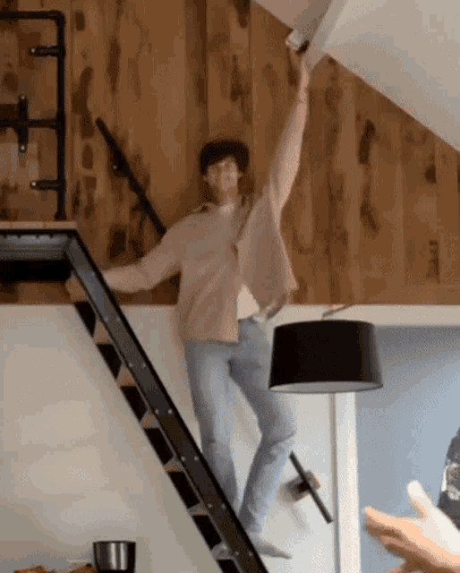 a man is standing on a staircase reaching for a lamp
