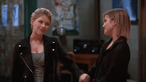 two women are shaking hands in a room while looking at each other .